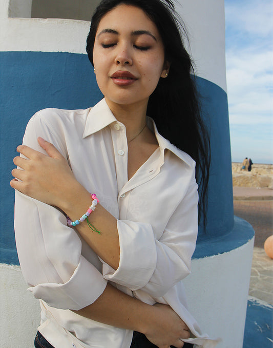 Woman wearing long sleeve Beige Silk Shirt against a blue and white wall