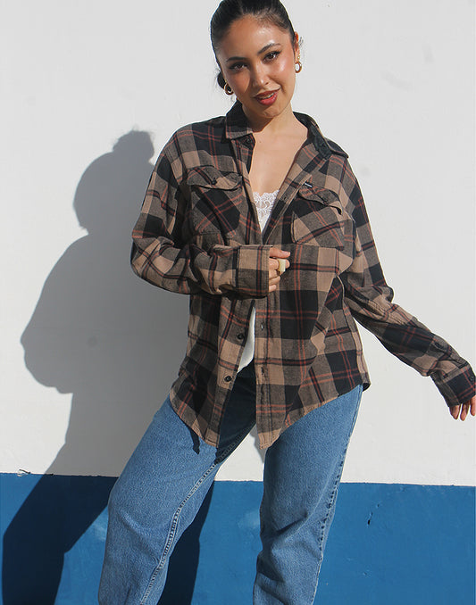 Woman wearing a brown plaid shirt and jeans against a white background