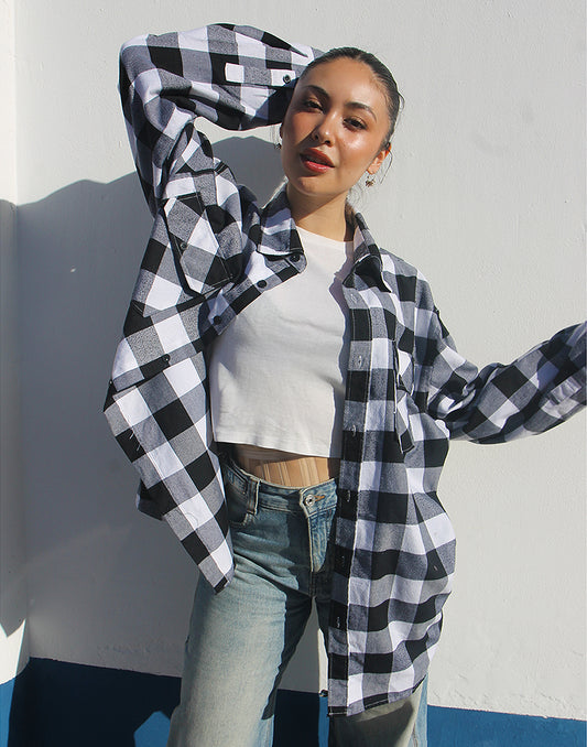 Person wearing the open black and white flannel shirt layered over a t-shirt for a casual, rugged look.