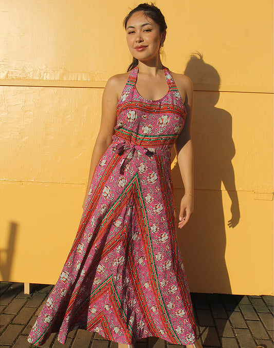woman wearing 70s pink sleeveless maxi dress against a yellow wall