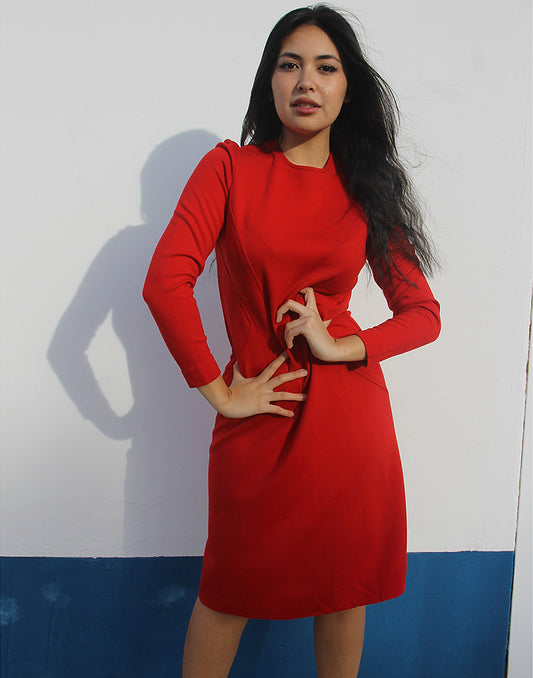 woman wearing long sleeve red wool dress against a white wall
