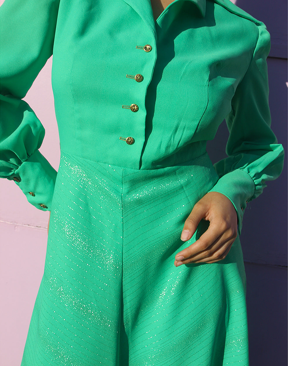 woman in green 70s long sleeve maxi dress against a pink wall 
