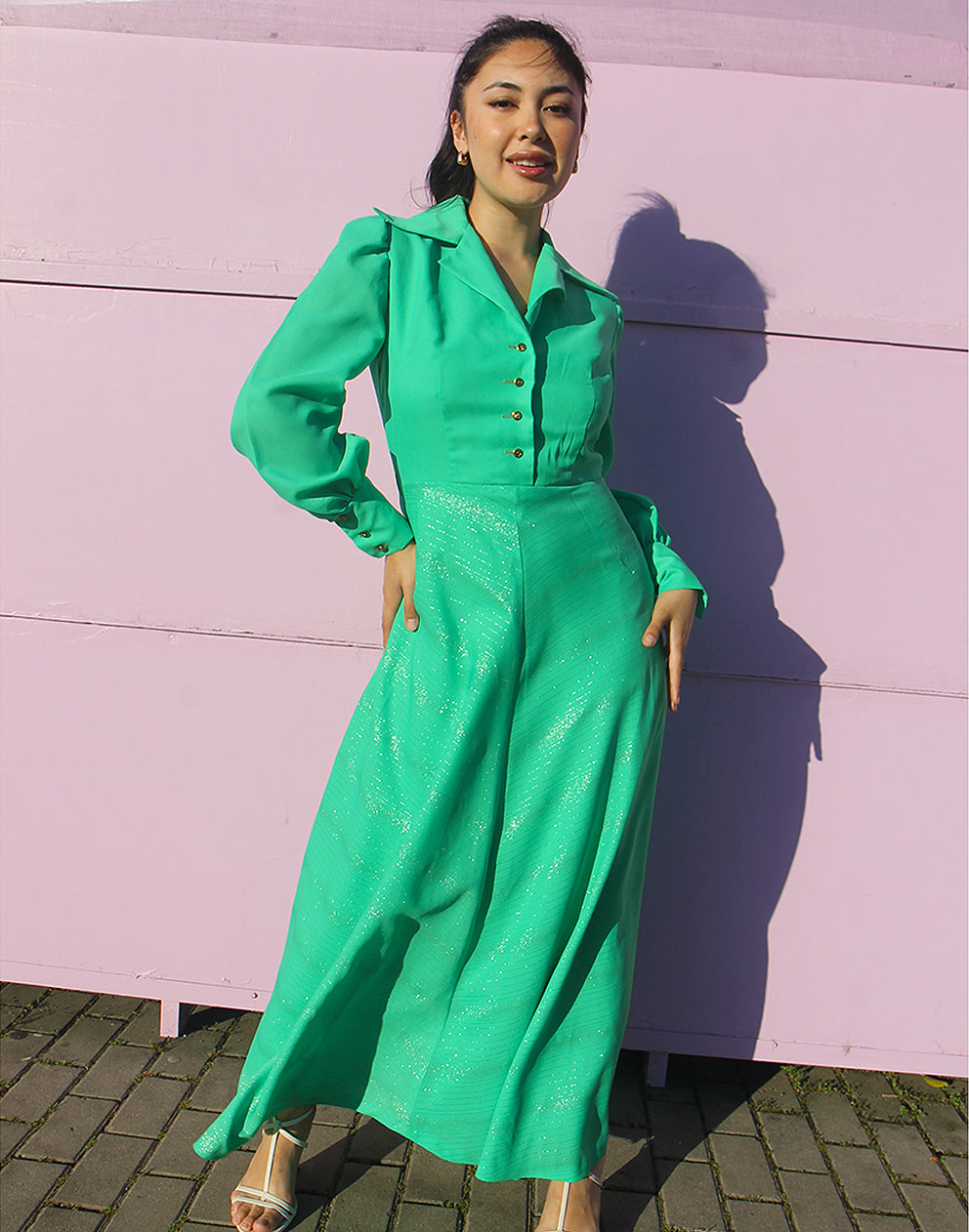woman in green 70s long sleeve maxi dress against a pink wall 