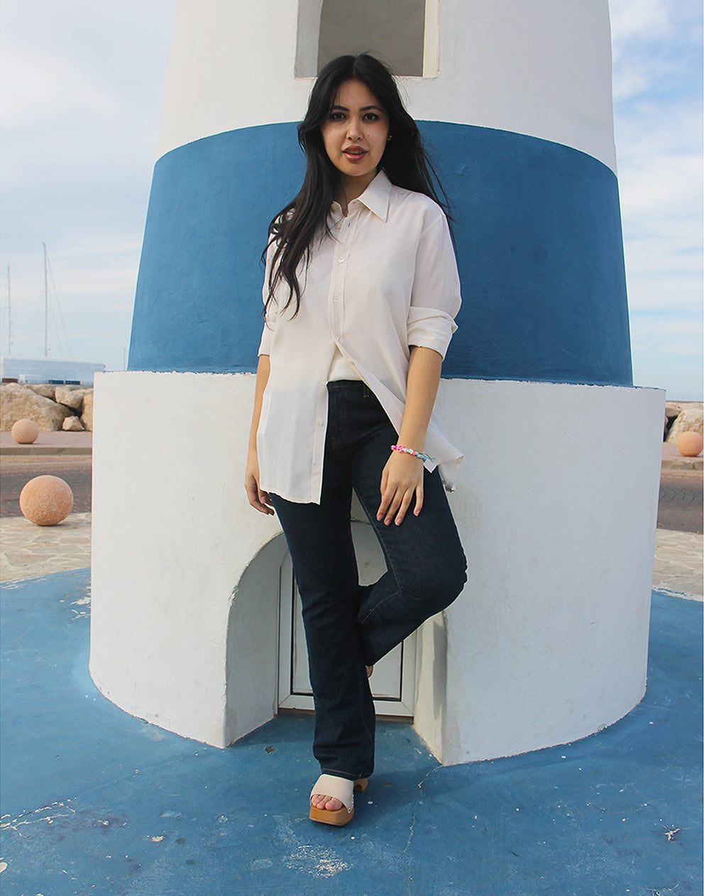 Woman wearing long sleeve Beige Silk Shirt against a blue and white wall