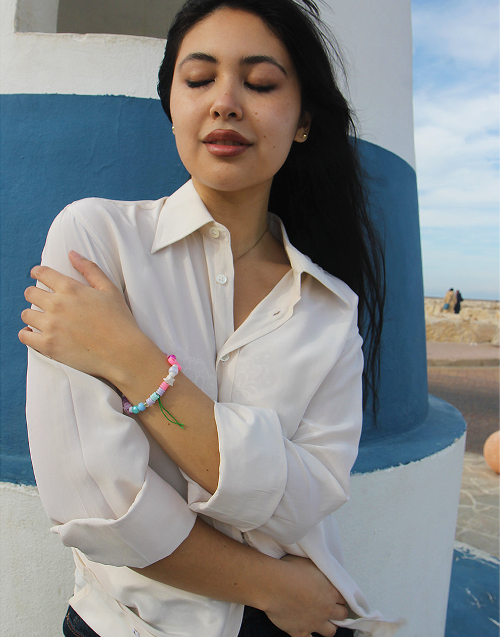 Woman wearing long sleeve Beige Silk Shirt against a blue and white wall