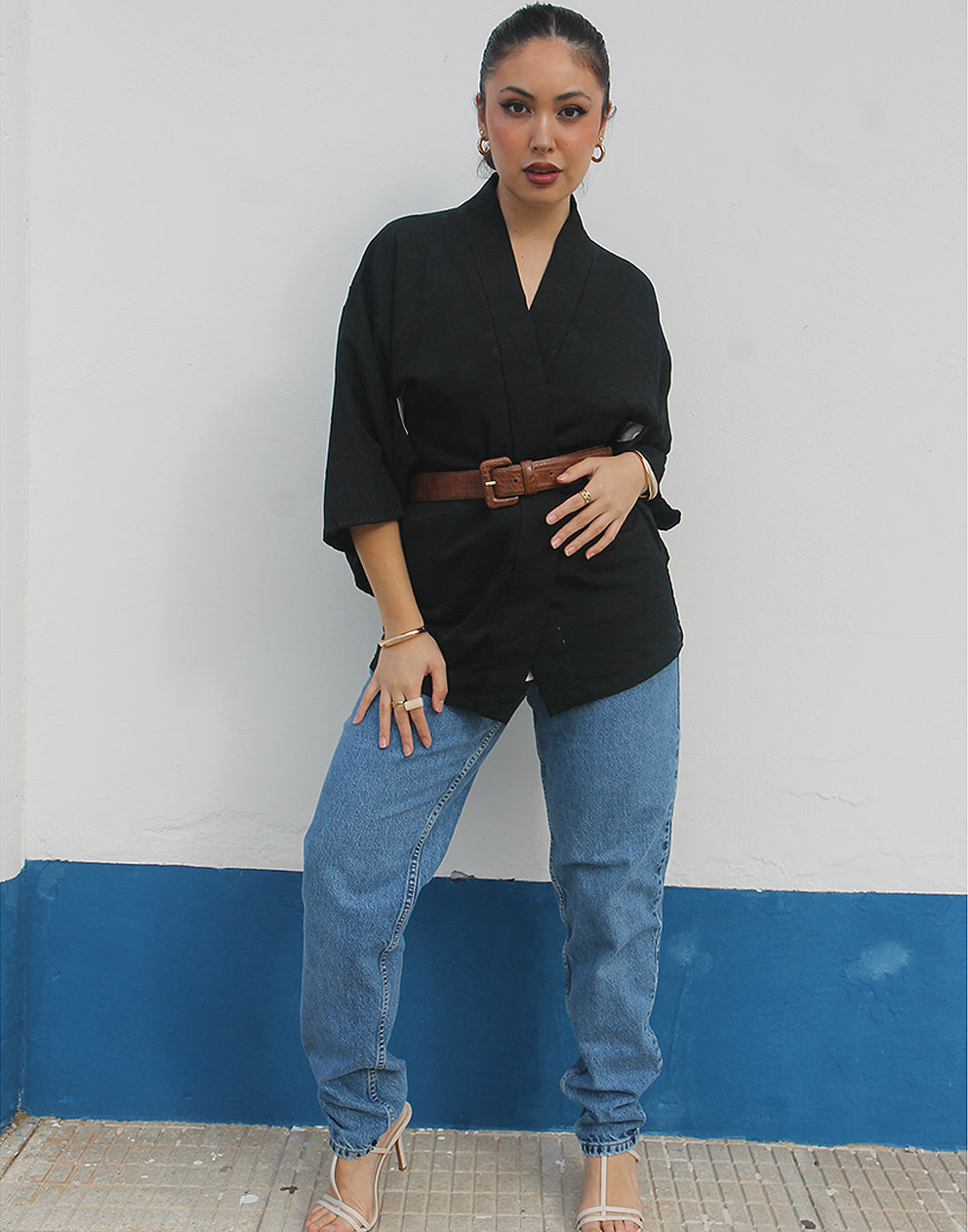woman wearing black silk haori kimono jacket against a white wall