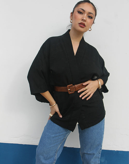 woman wearing black silk haori kimono jacket against a white wall