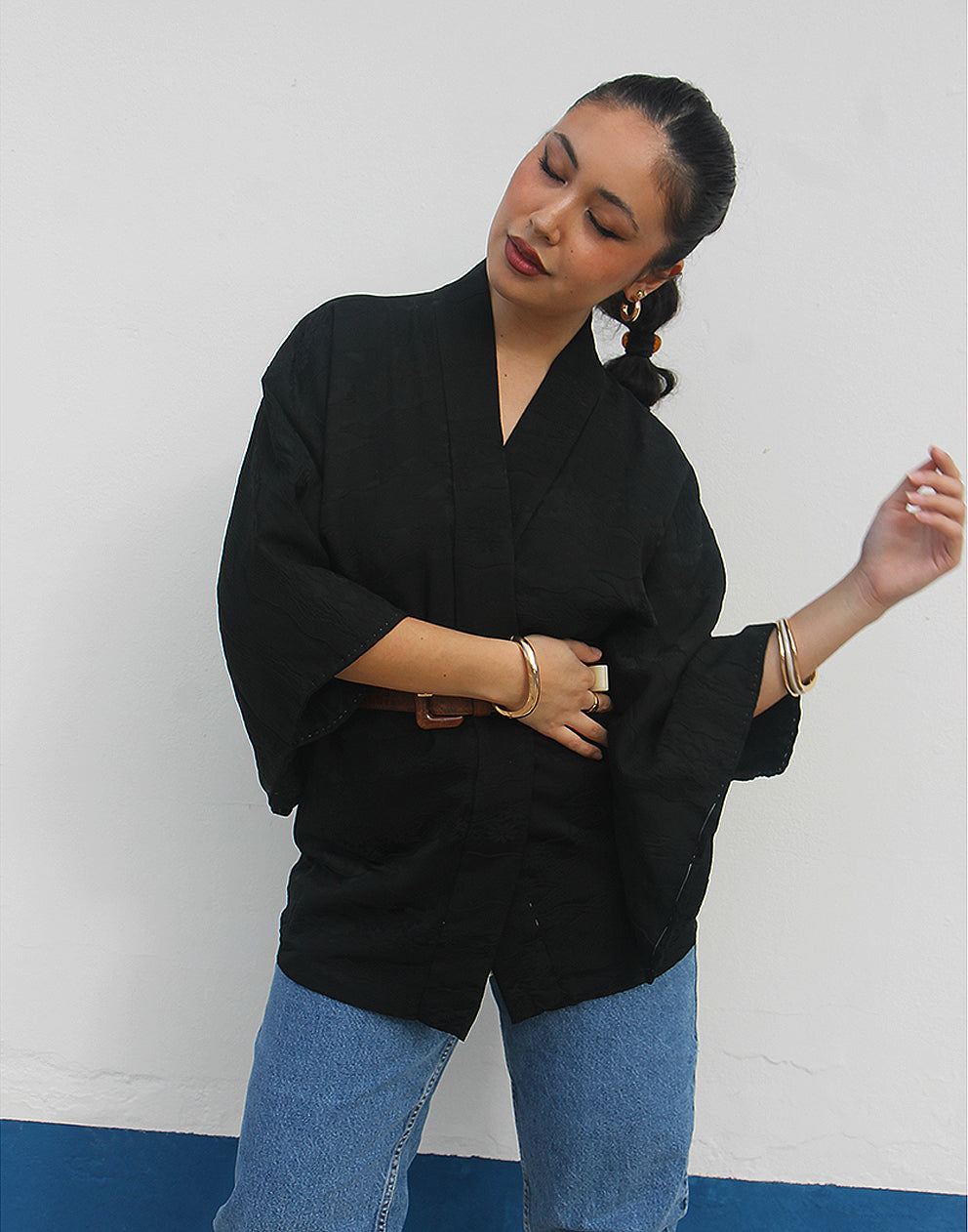 woman wearing black silk haori kimono jacket against a white wall