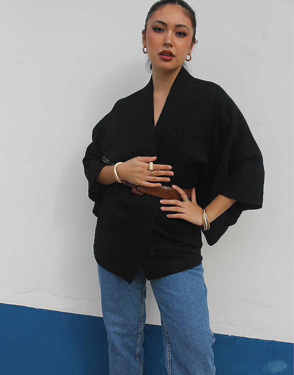 woman wearing black silk haori kimono jacket against a white wall
