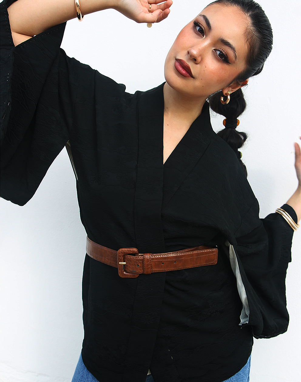 woman wearing black silk haori kimono jacket against a white wall