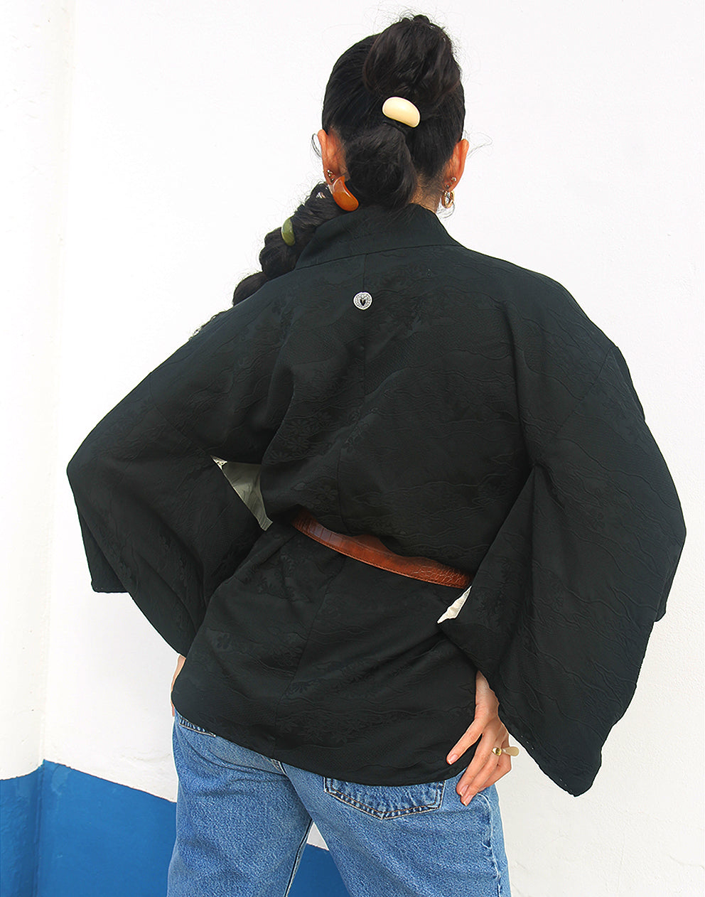 woman wearing black silk haori kimono jacket against a white wall
