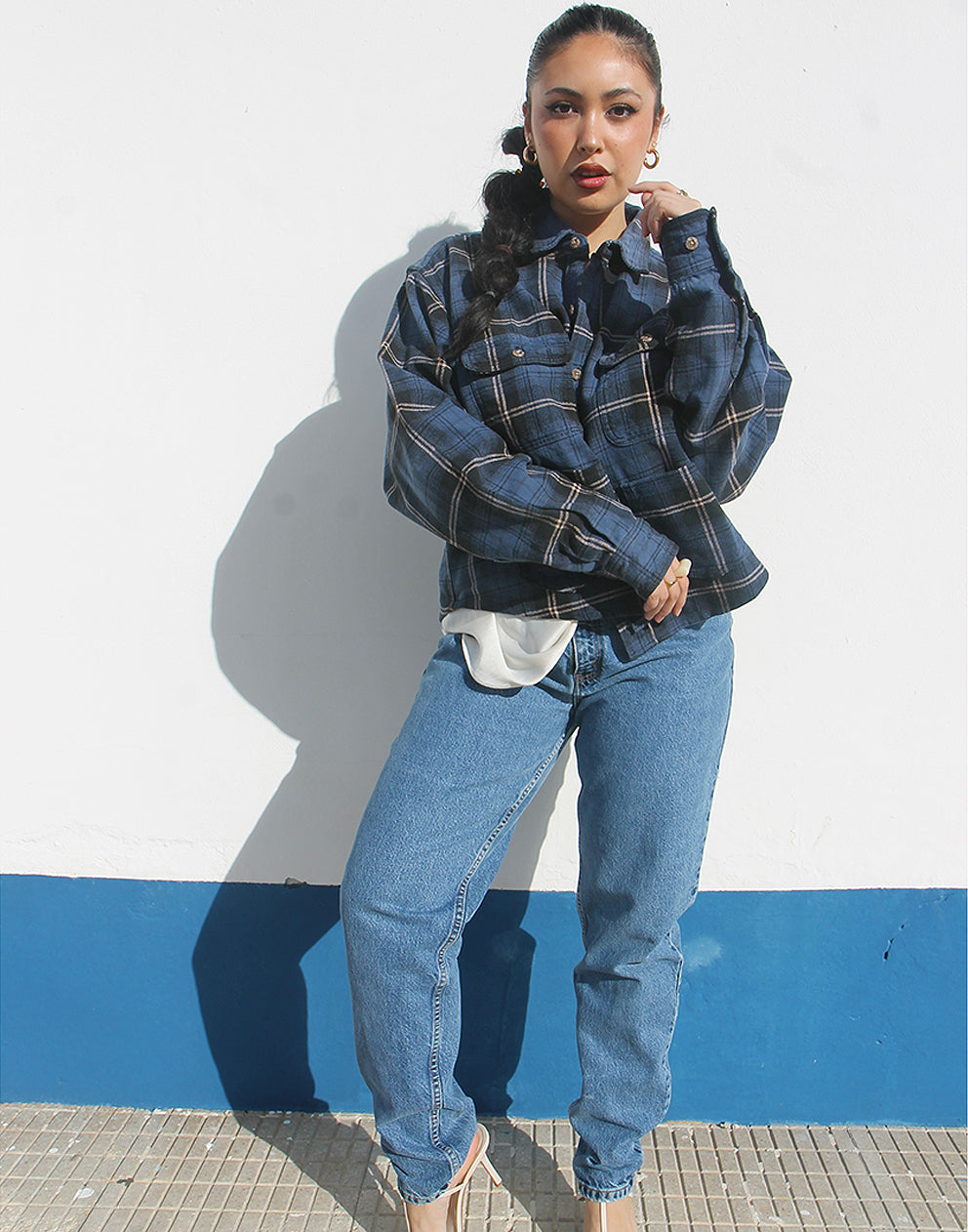Person wearing a blue plaid shirt and jeans against a white background