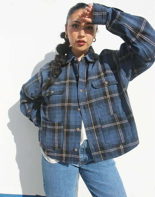 Person wearing a blue plaid shirt and jeans against a white background
