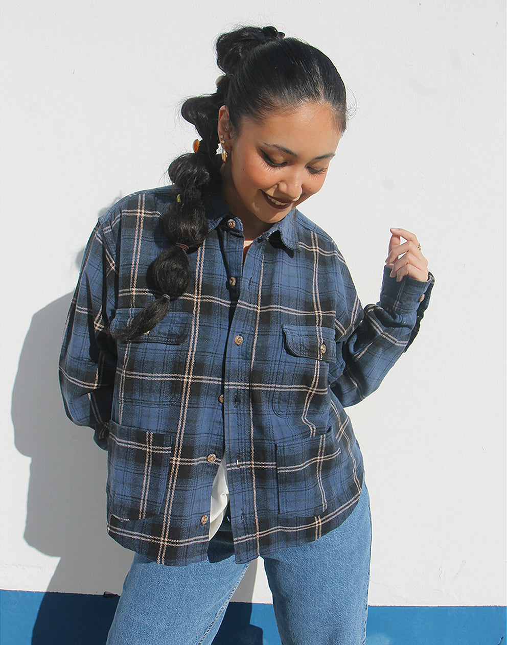Person wearing a blue plaid shirt and jeans against a white background