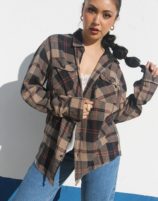 Woman wearing a brown plaid shirt and jeans against a white background