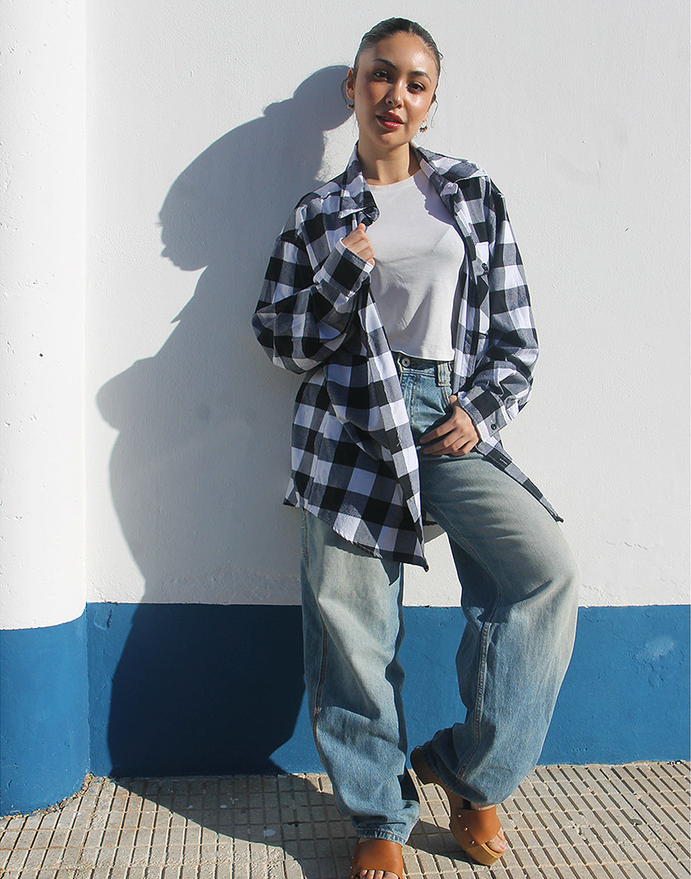 Person wearing the open black and white flannel shirt layered over a t-shirt for a casual, rugged look.