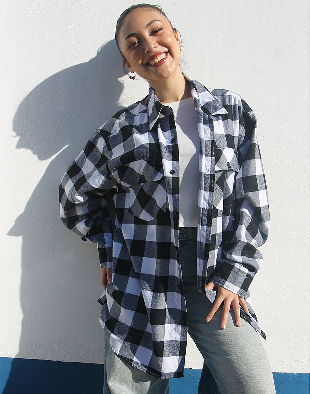 Person wearing the open black and white flannel shirt layered over a t-shirt for a casual, rugged look.