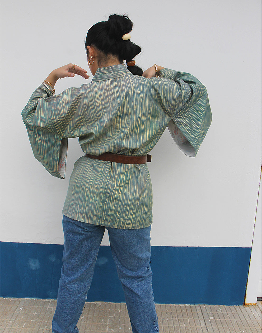 WOMAN WEARING GREEN HAORI KIMONO JACKET AGAINST A WHITE WALL