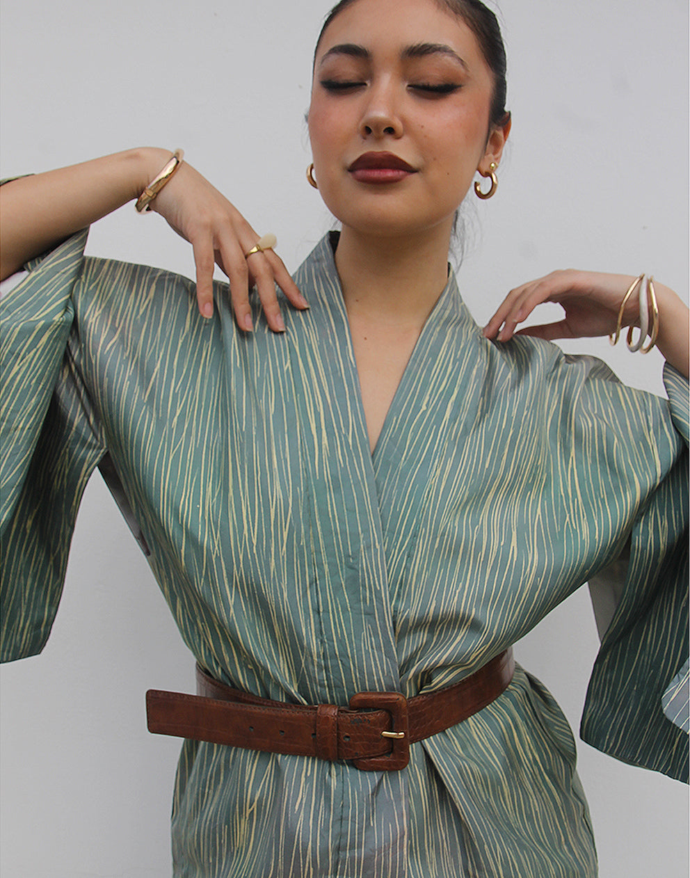 WOMAN WEARING GREEN HAORI KIMONO JACKET AGAINSTA A WHITE WALL