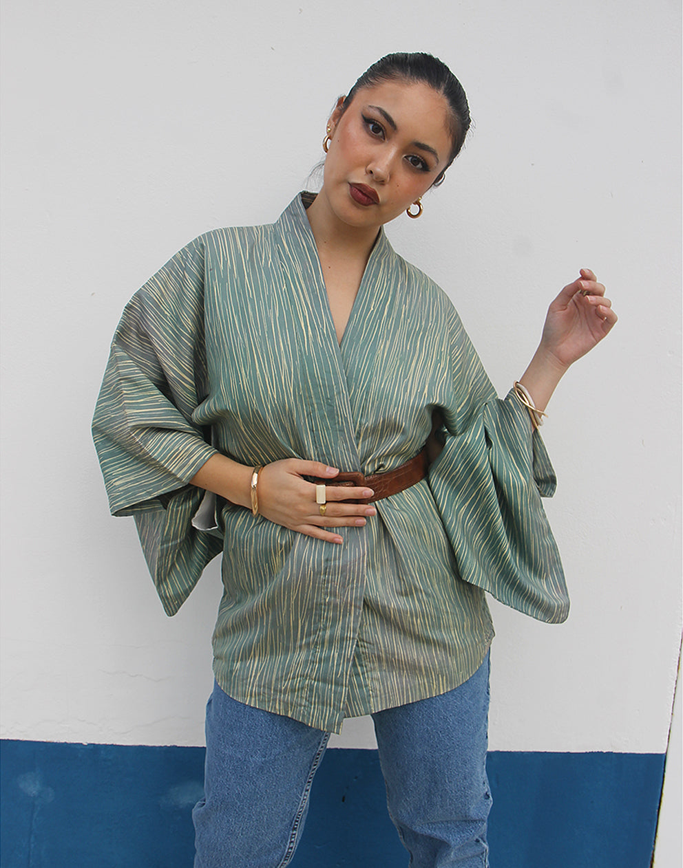 WOMAN WEARING GREEN HAORI KIMONO JACKET AGAINST A WHITE WALL