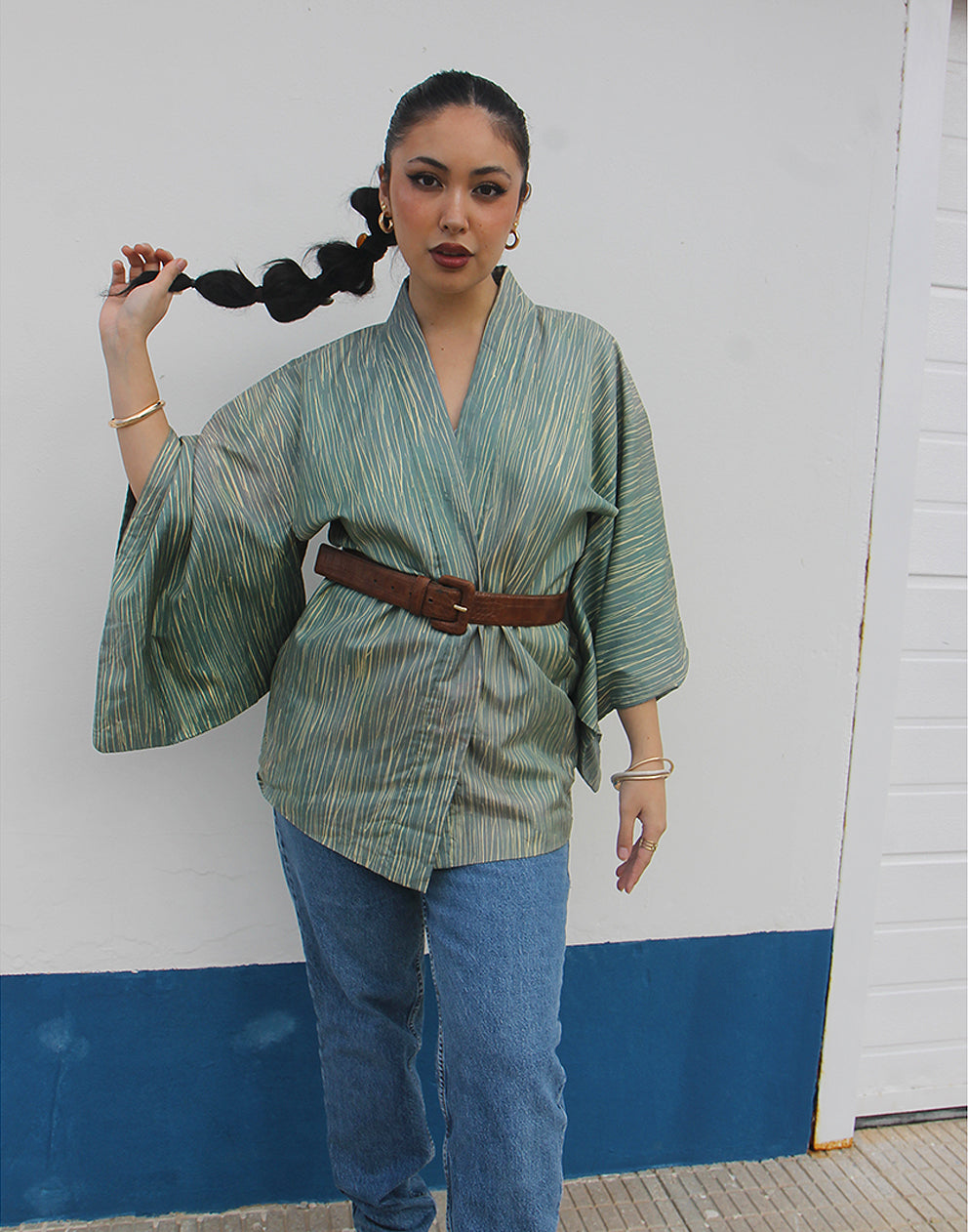 WOMAN WEARING GREEN HAORI KIMONO JACKET AGAINSTA A WHITE WALL