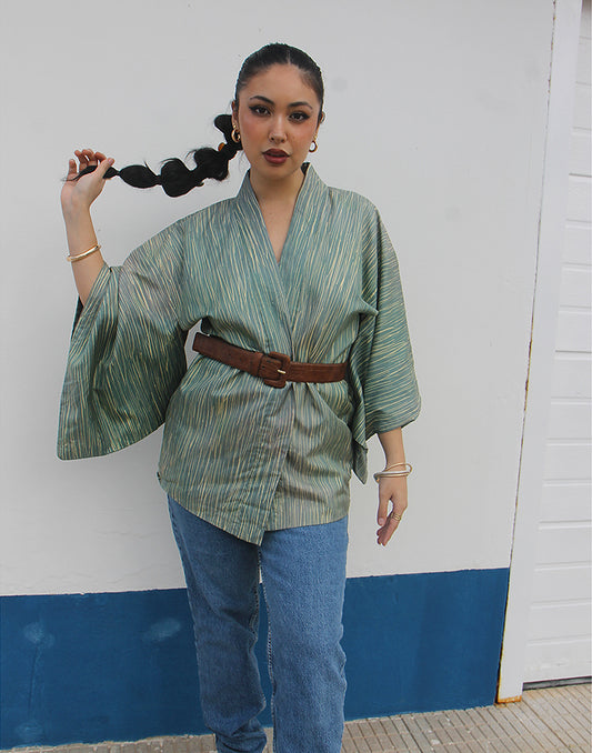 WOMAN WEARING GREEN HAORI KIMONO JACKET AGAINSTA A WHITE WALL