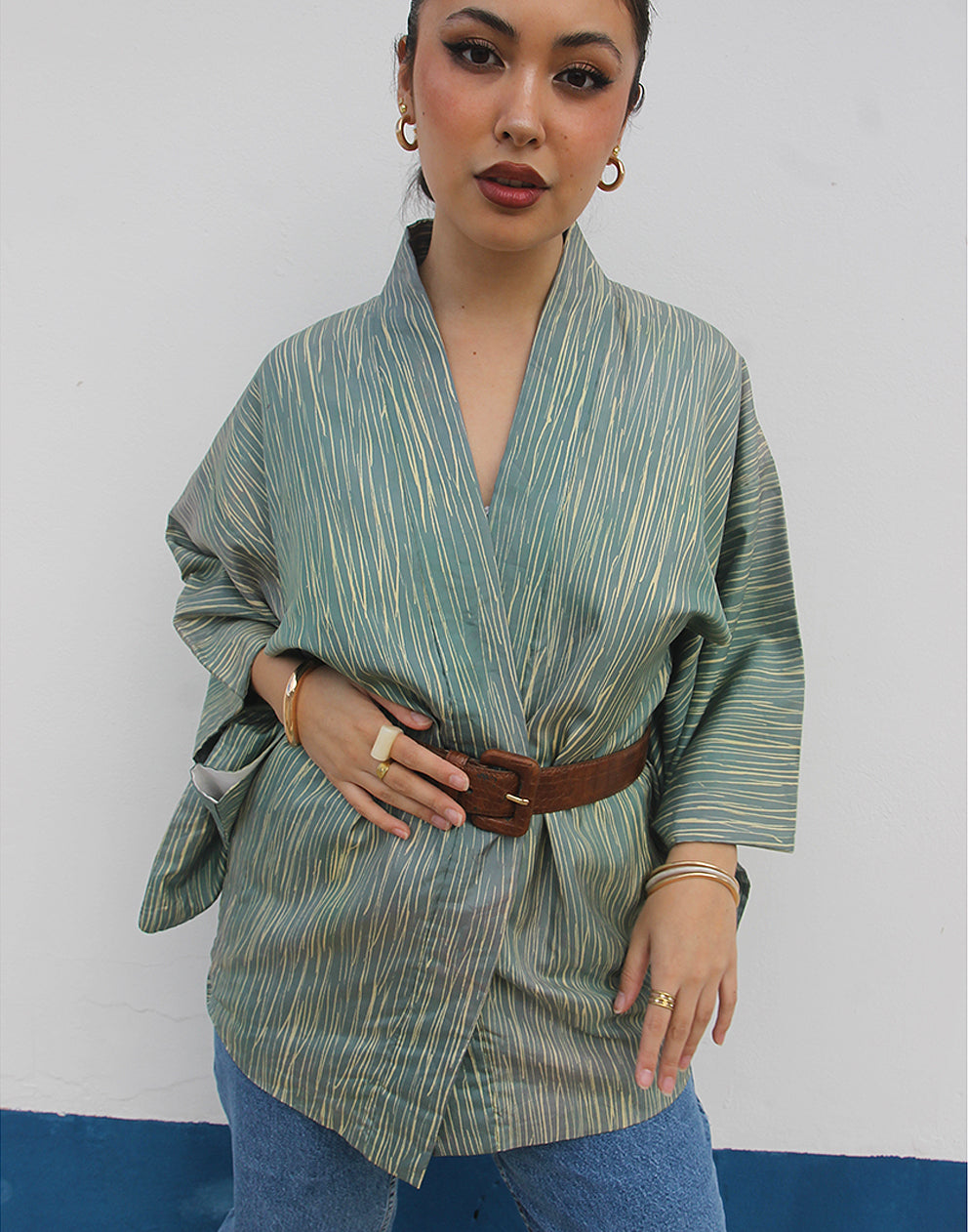 WOMAN WEARING GREEN HAORI KIMONO JACKET AGAINST A WHITE WALL