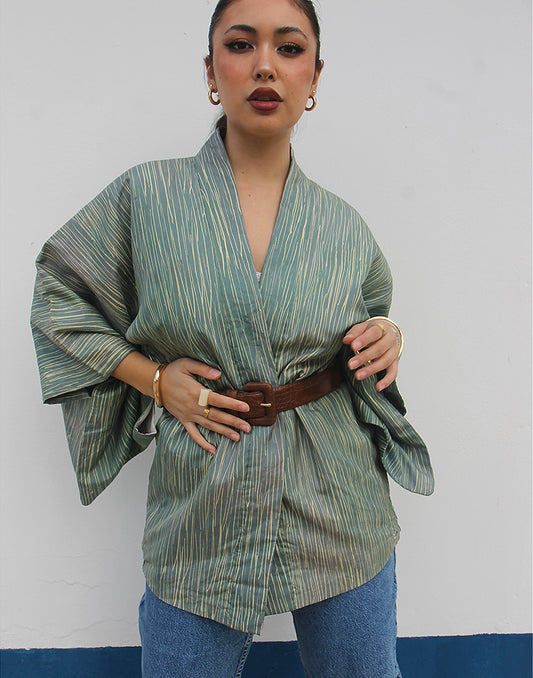 WOMAN WEARING GREEN HAORI KIMONO JACKET AGAINST A WHITE WALL