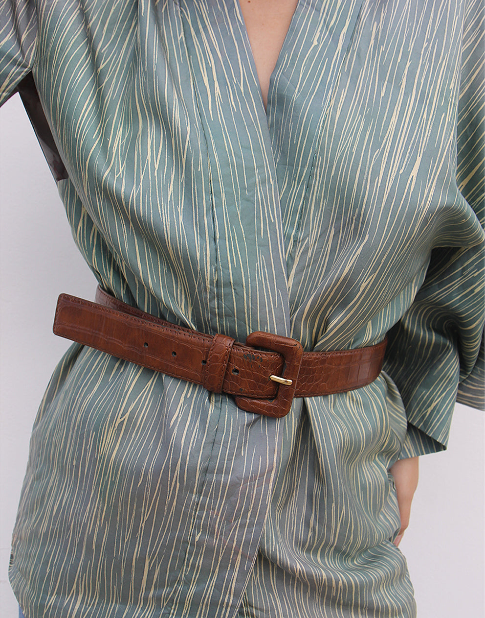 WOMAN WEARING GREEN HAORI KIMONO JACKET AGAINST A WHITE WALL