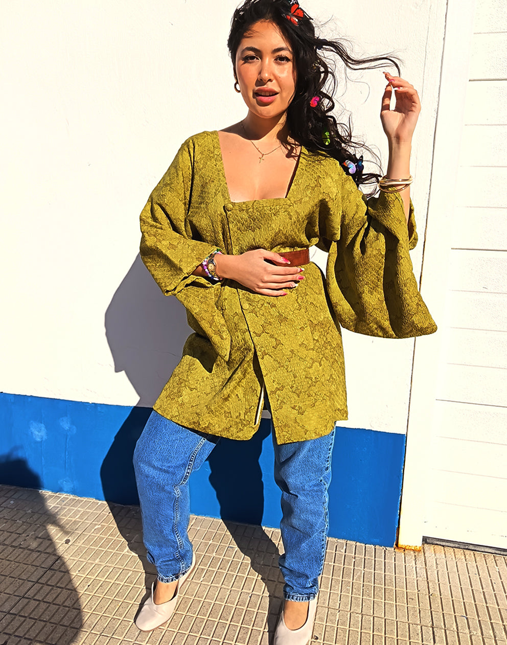 Person wearing a green textured Michiyuki kimono with a belt, standing against a blue and white background.