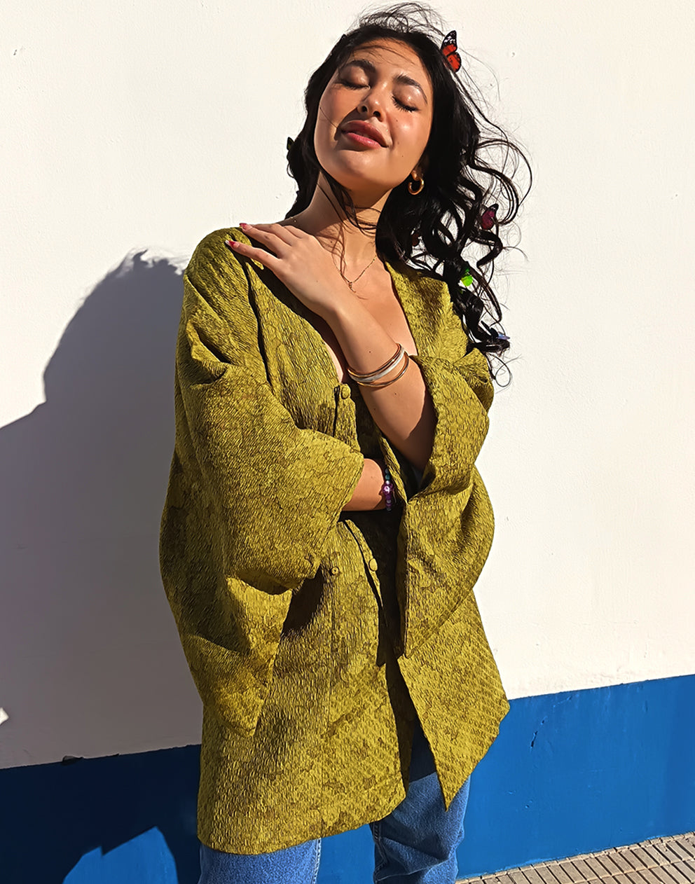 Person wearing a green textured Michiyuki kimono with a belt, standing against a blue and white background.