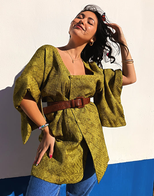 Person wearing a green textured Michiyuki kimono with a belt, standing against a blue and white background.