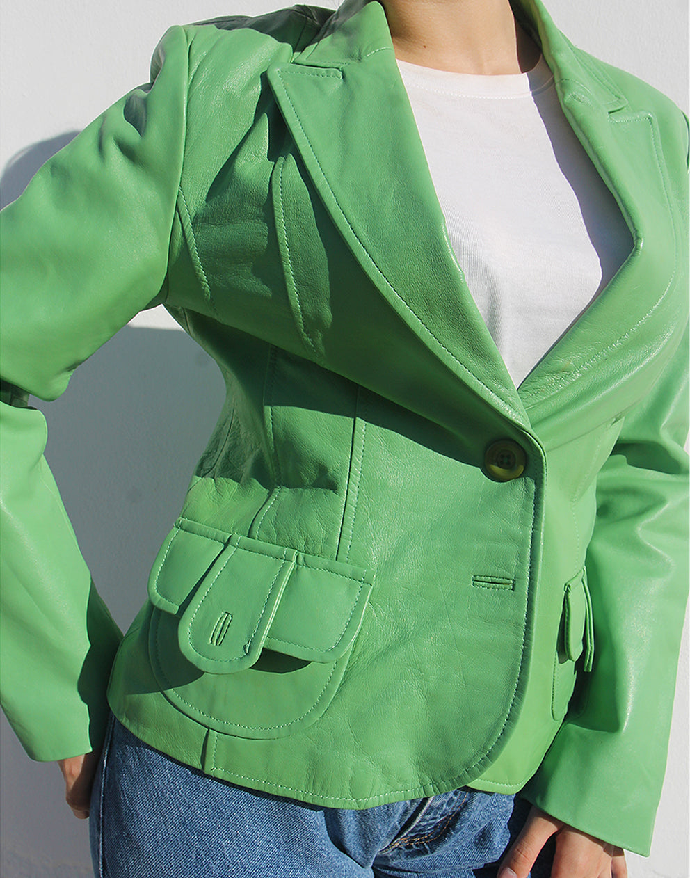 Close-up of the smooth green leather texture and the front pocket stitching.