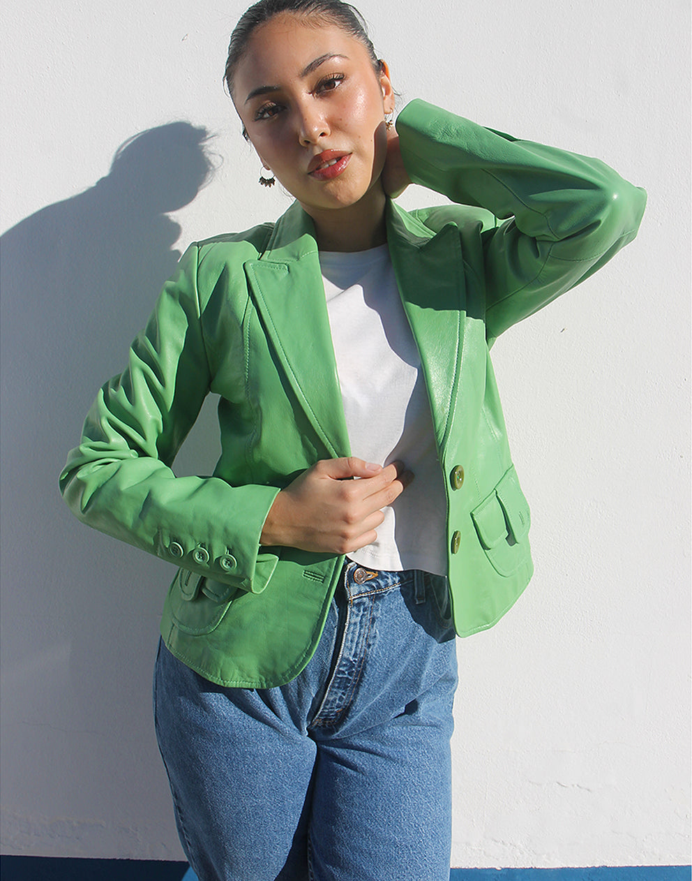 Front view of a green leather jacket featuring a V-neckline and a single-button closure.