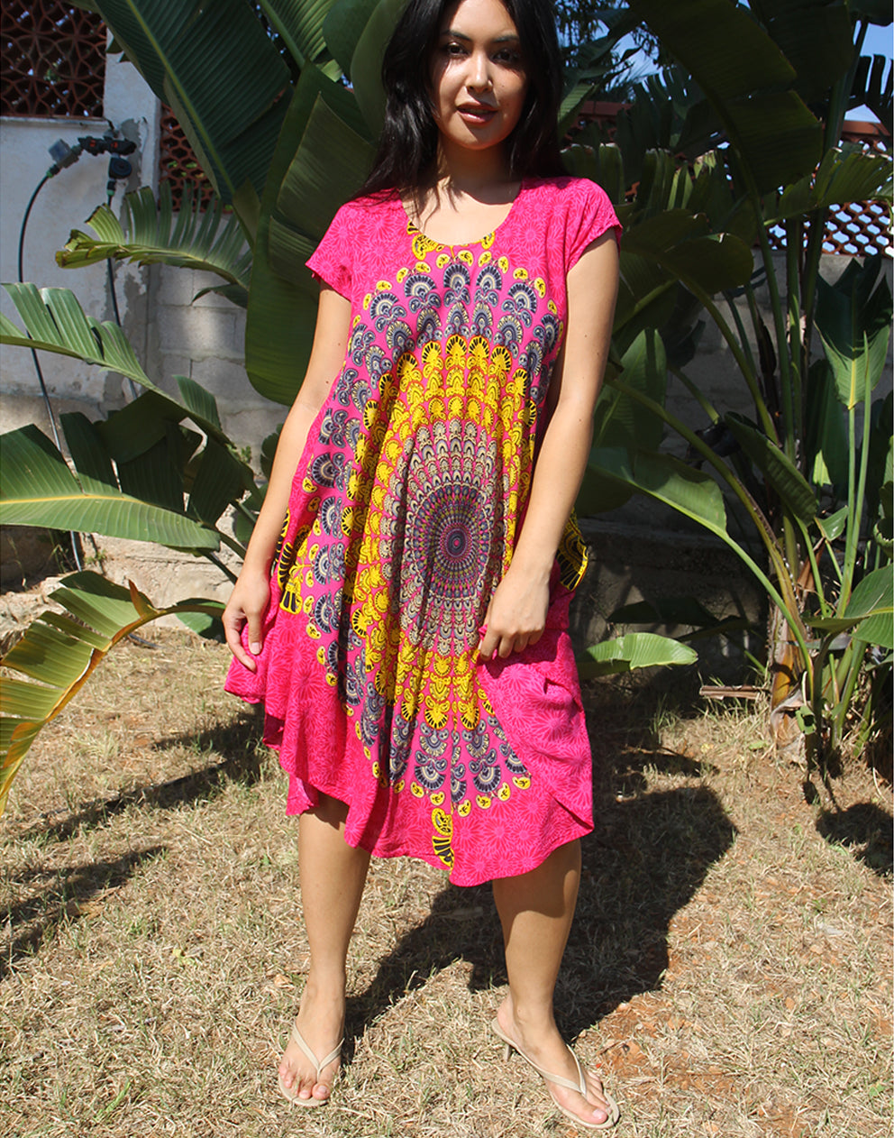 A woman wearing a bright pink beach dress with a large yellow print, standing outdoors