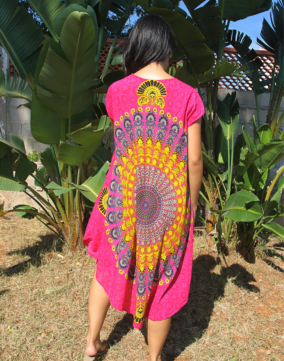 A woman wearing a bright pink beach dress with a large yellow print, standing outdoors