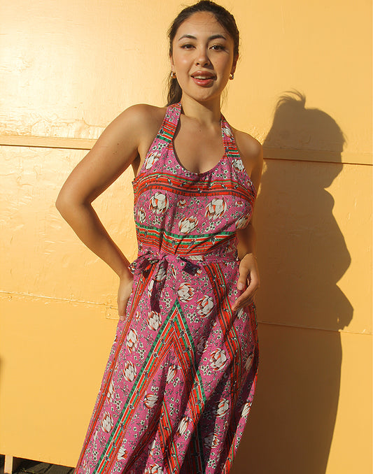 woman wearing 70s pink sleeveless maxi dress against a yellow wall
