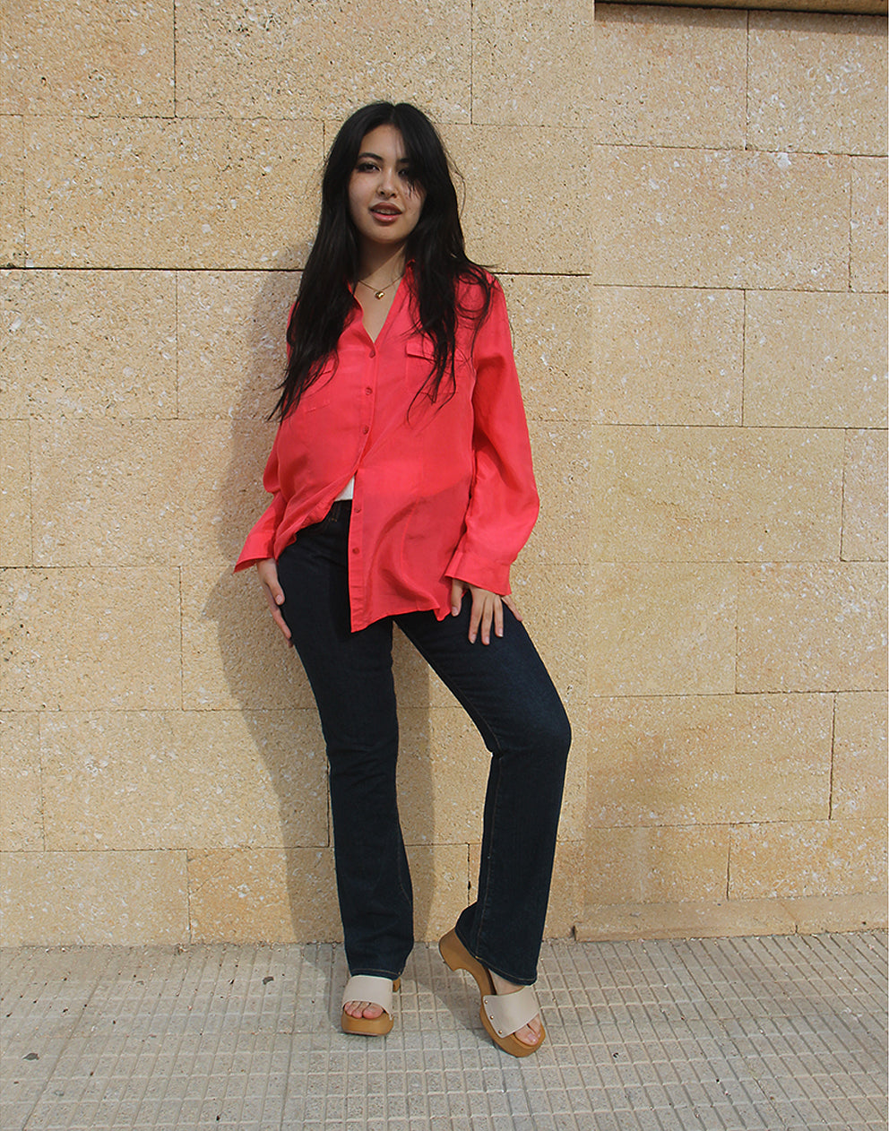 woman wearing long sleeve pink silk shirt against a brown wall