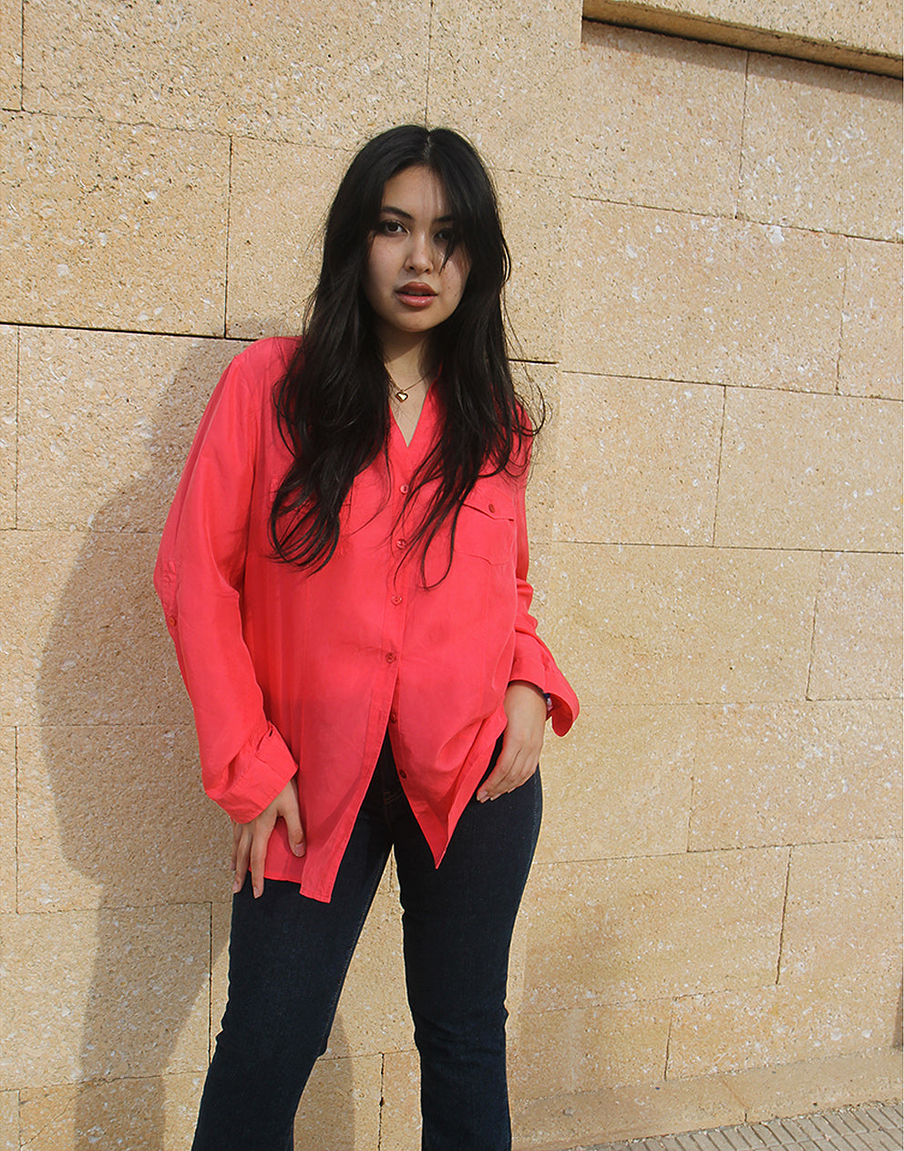woman wearing long sleeve pink silk shirt against a brown wall