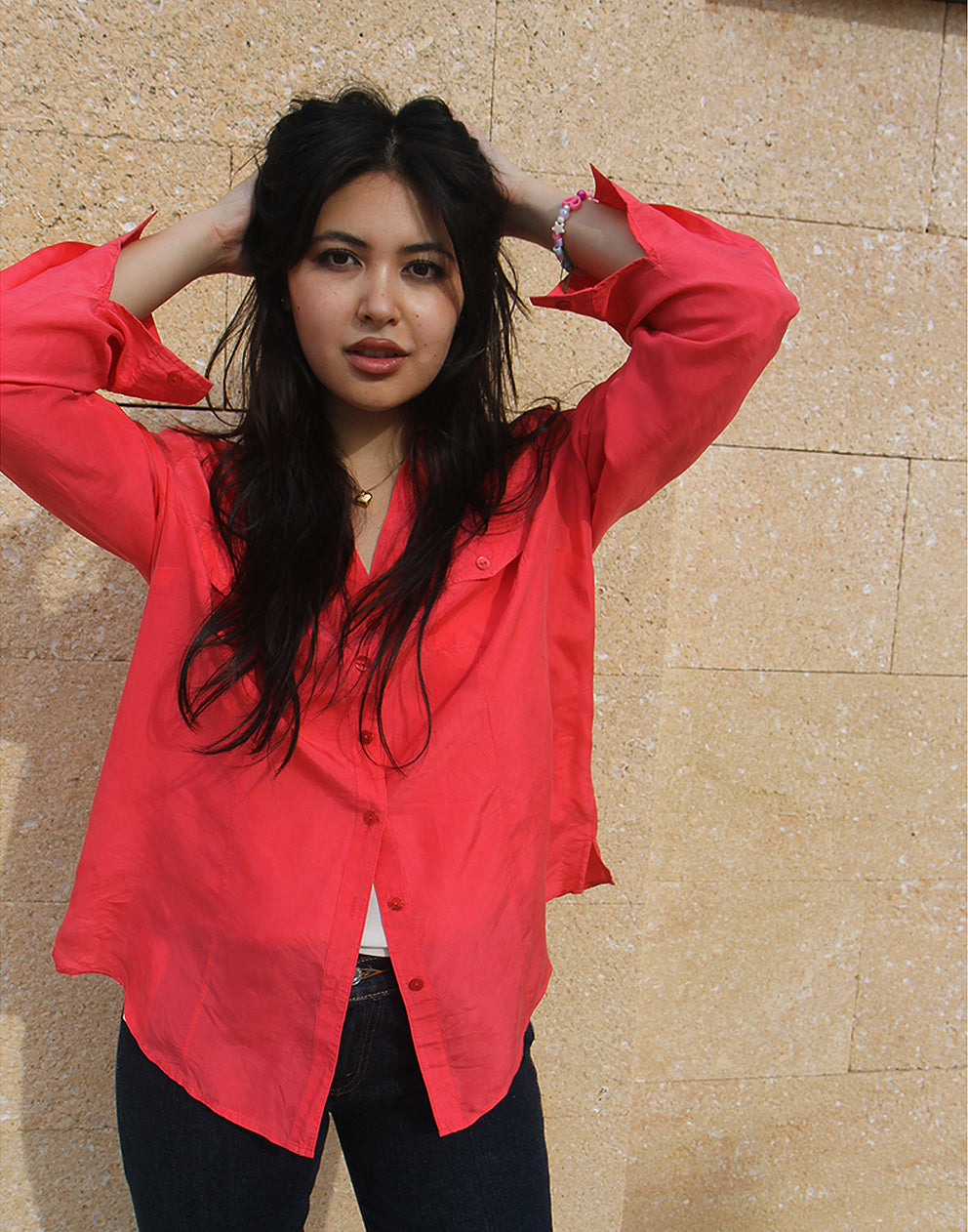 woman wearing long sleeve pink silk shirt against a brown wall