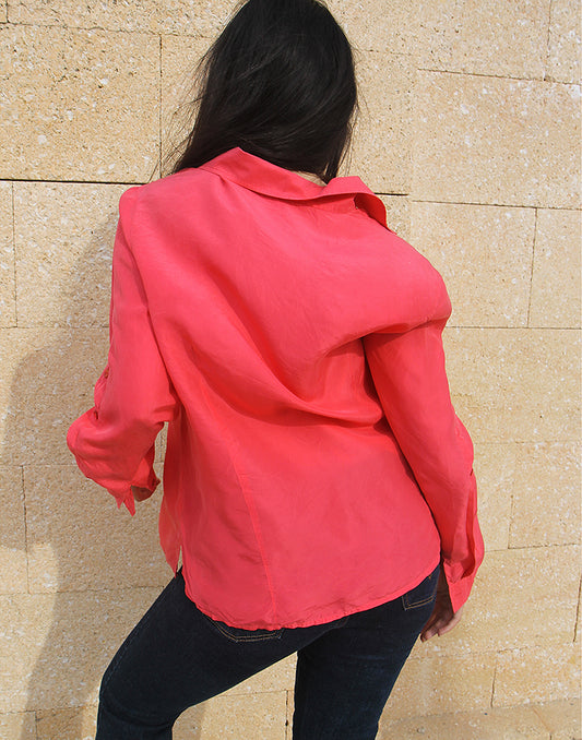 woman wearing long sleeve pink silk shirt against a brown wall