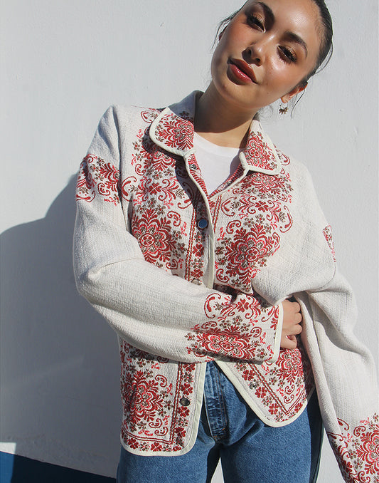 Front view of women’s cream and red floral tapestry coat with classic collar and snap buttons.