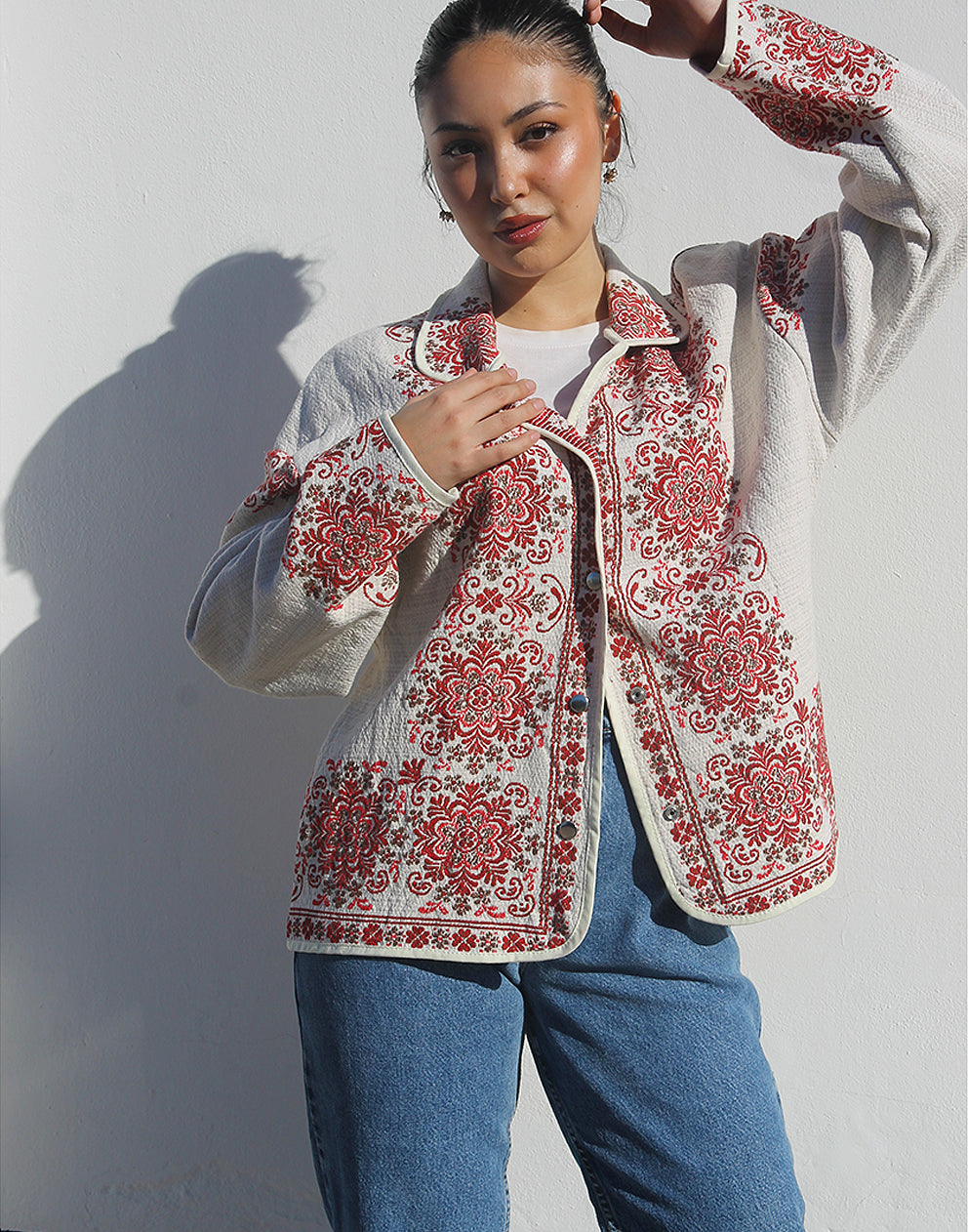 Front view of women’s cream and red floral tapestry coat with classic collar and snap buttons.