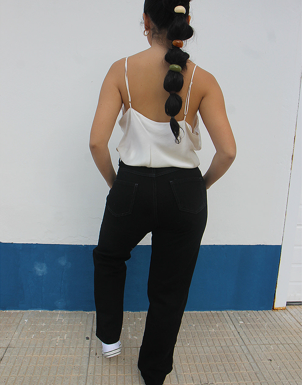 woman wearing black straight leg high rise jeans against a white wall