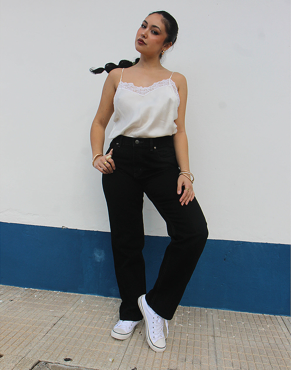 woman wearing black straight leg high rise jeans against a white wall