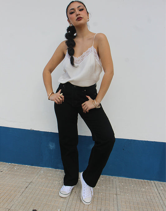 woman wearing black straight leg high rise jeans against a white wall