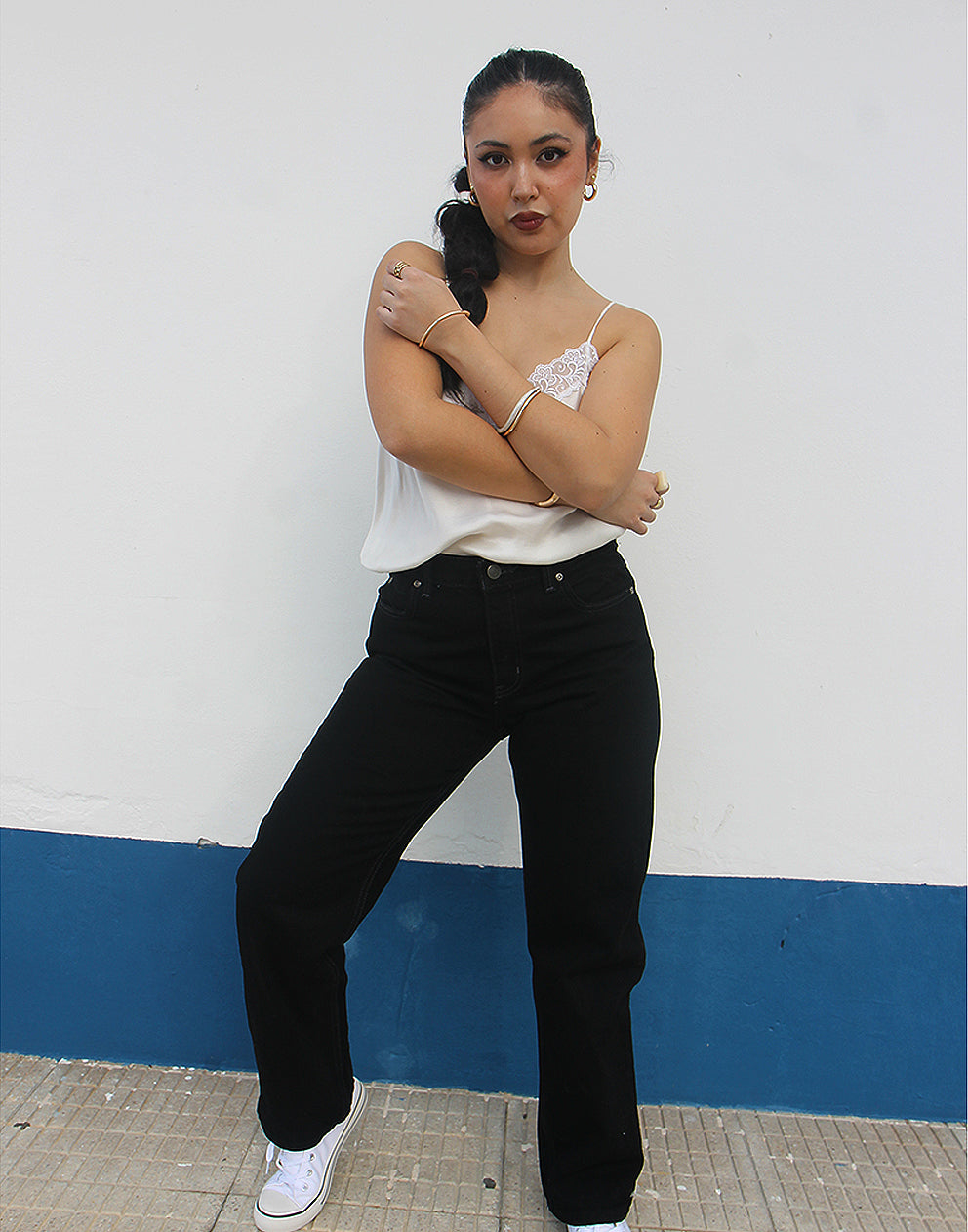 woman wearing black straight leg high rise jeans against a white wall