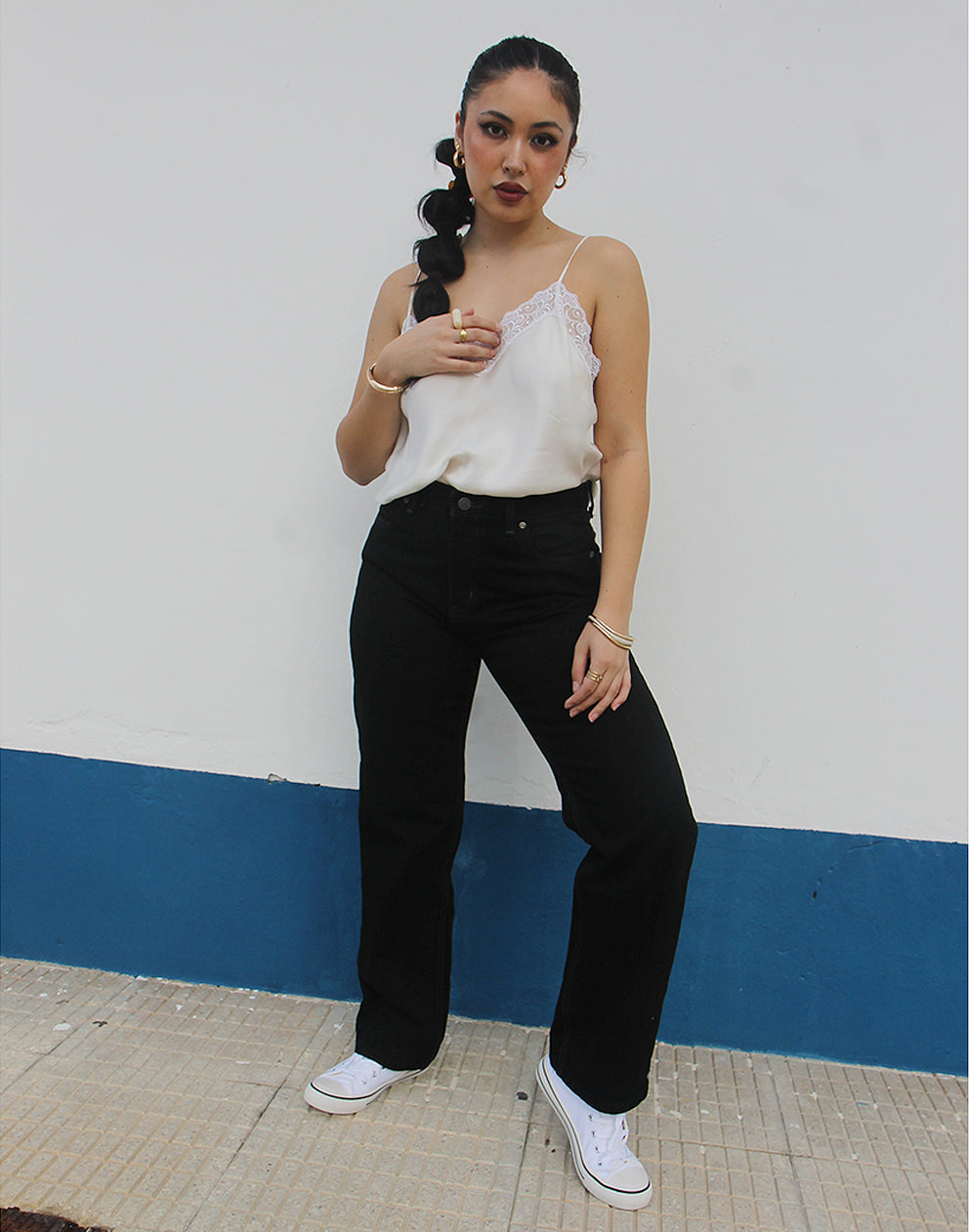 woman wearing black straight leg high rise jeans against a white wall