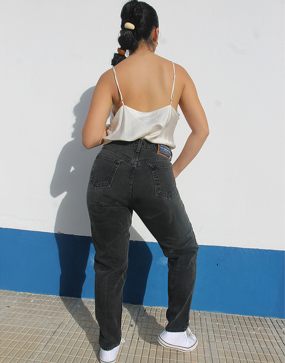 Woman wearing vintage Liz Clairborne jeans against a white wall